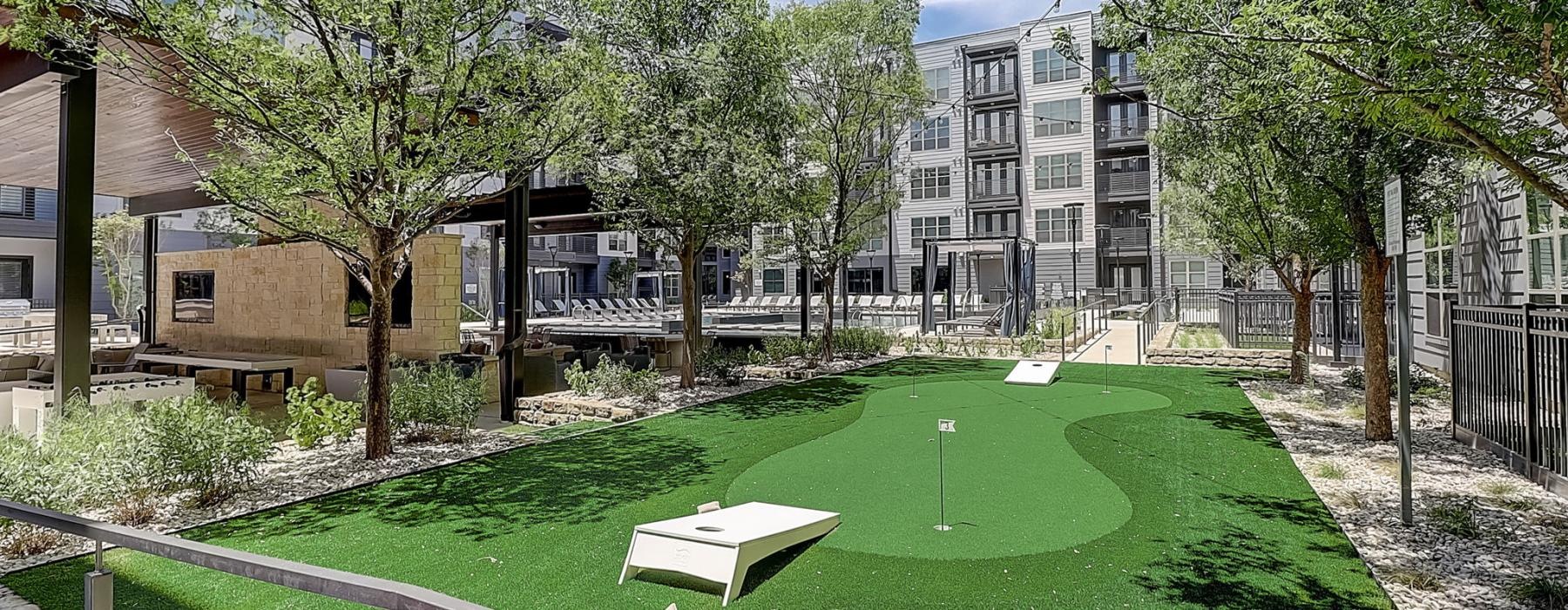 a large green lawn with trees and buildings in the background