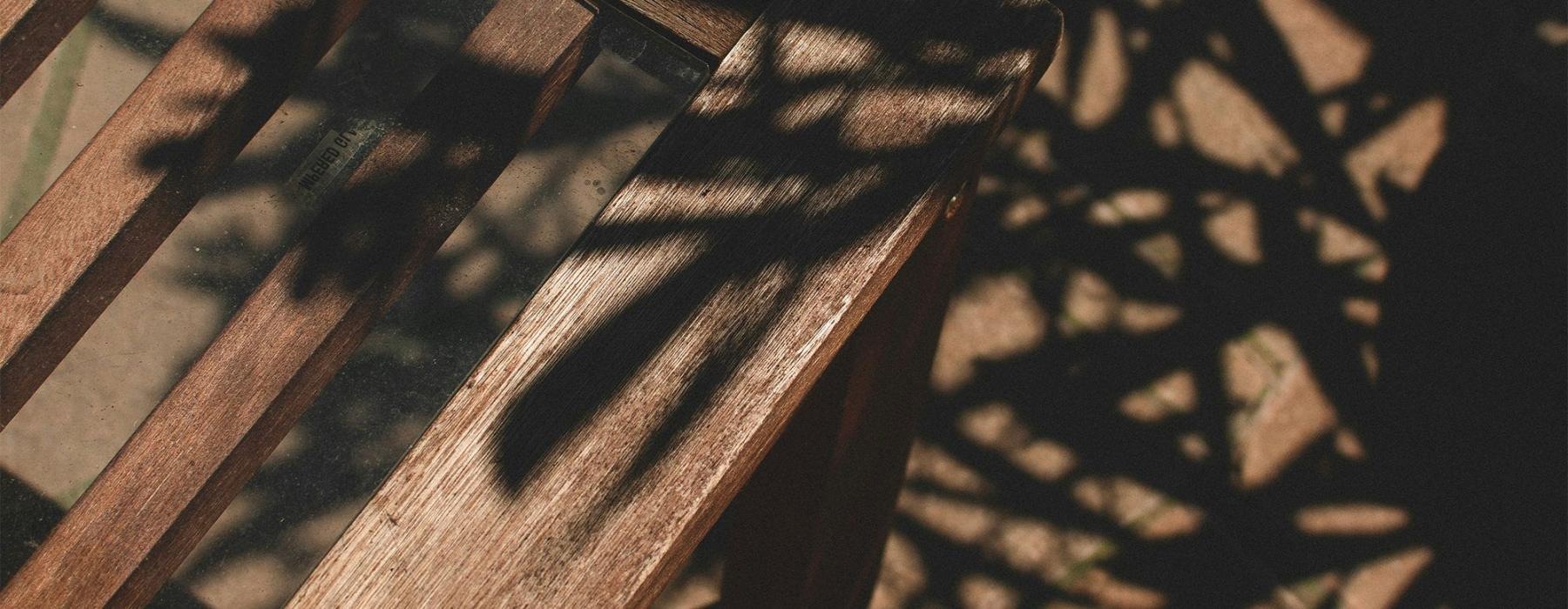 a wooden chair with shadows of leaves